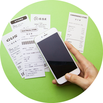 hand holding a smart phone above a pile of receipts against a green background